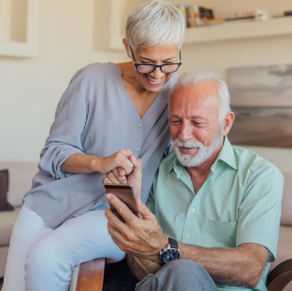 A retired couple looking at a phone together at home